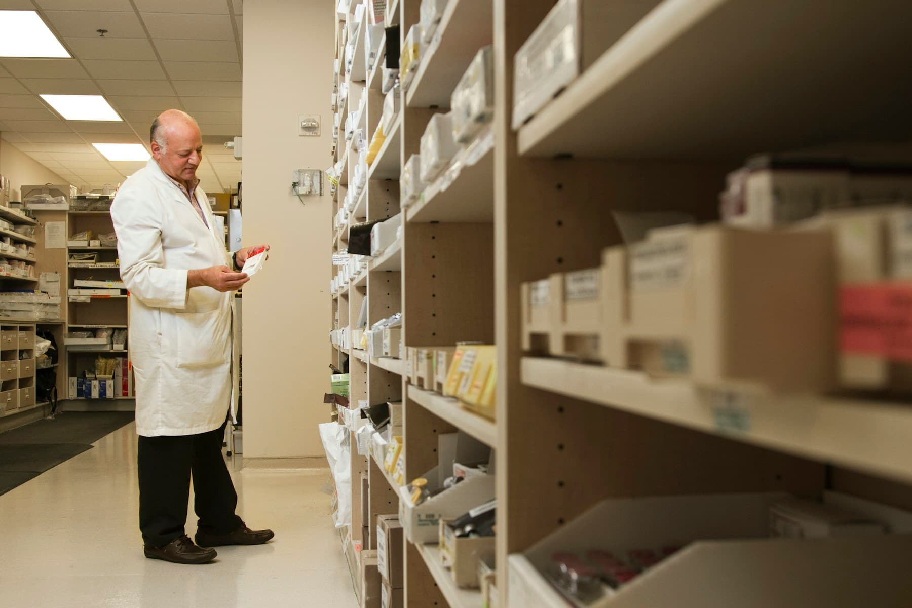 Pharmacy professional working beside medicine shelves